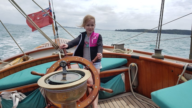 Young girl holding into the boat wheel